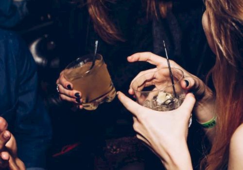 People are enjoying themselves at a social gathering, holding drinks and engaging in conversation.