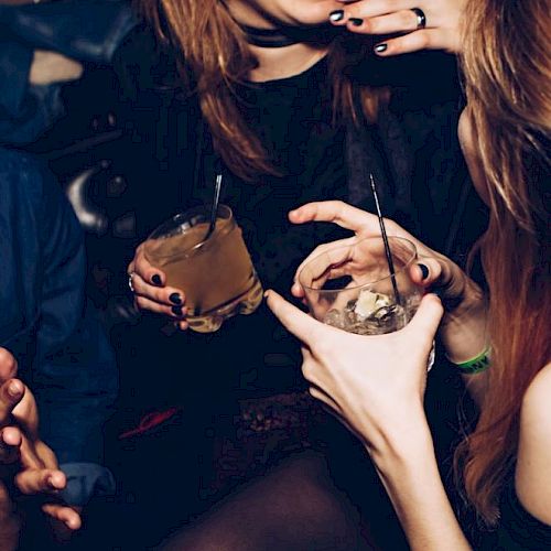 People are enjoying themselves at a social gathering, holding drinks and engaging in conversation.