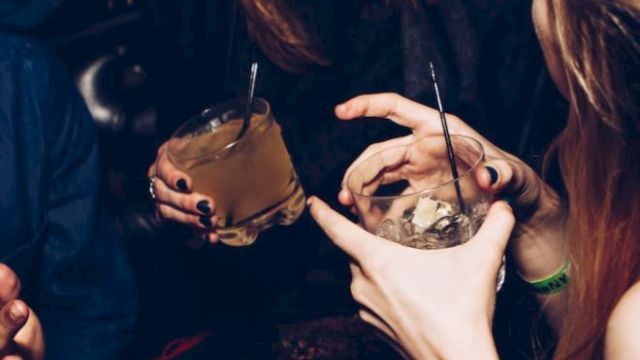 People are enjoying themselves at a social gathering, holding drinks and engaging in conversation.