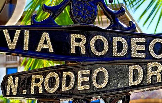 Close up image of Rodeo drive street signs that are black and gold in a think cast iron metal.