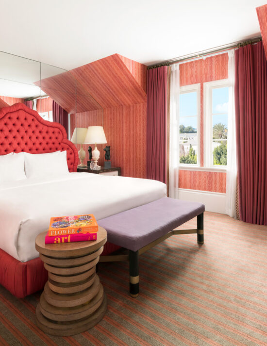 Hotel room near rodeo drive at Maison 140 with a large mirror wall, king bed, and pink walls.
