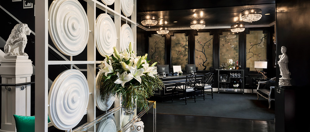 Dark and moody hotel lobby with black walls, gotic wall paper, and a white disc wall divider.